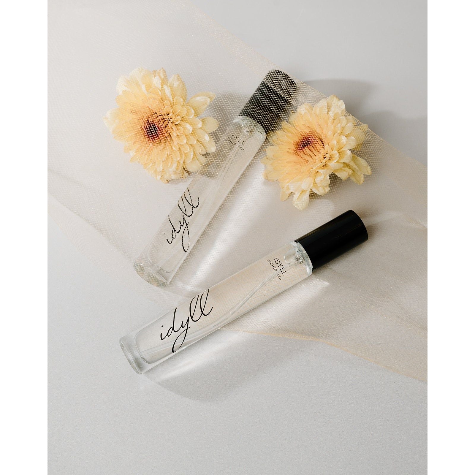 Lifestyle photo showing IDYLL Perfume Travel Spray in use - Orchid + Ash