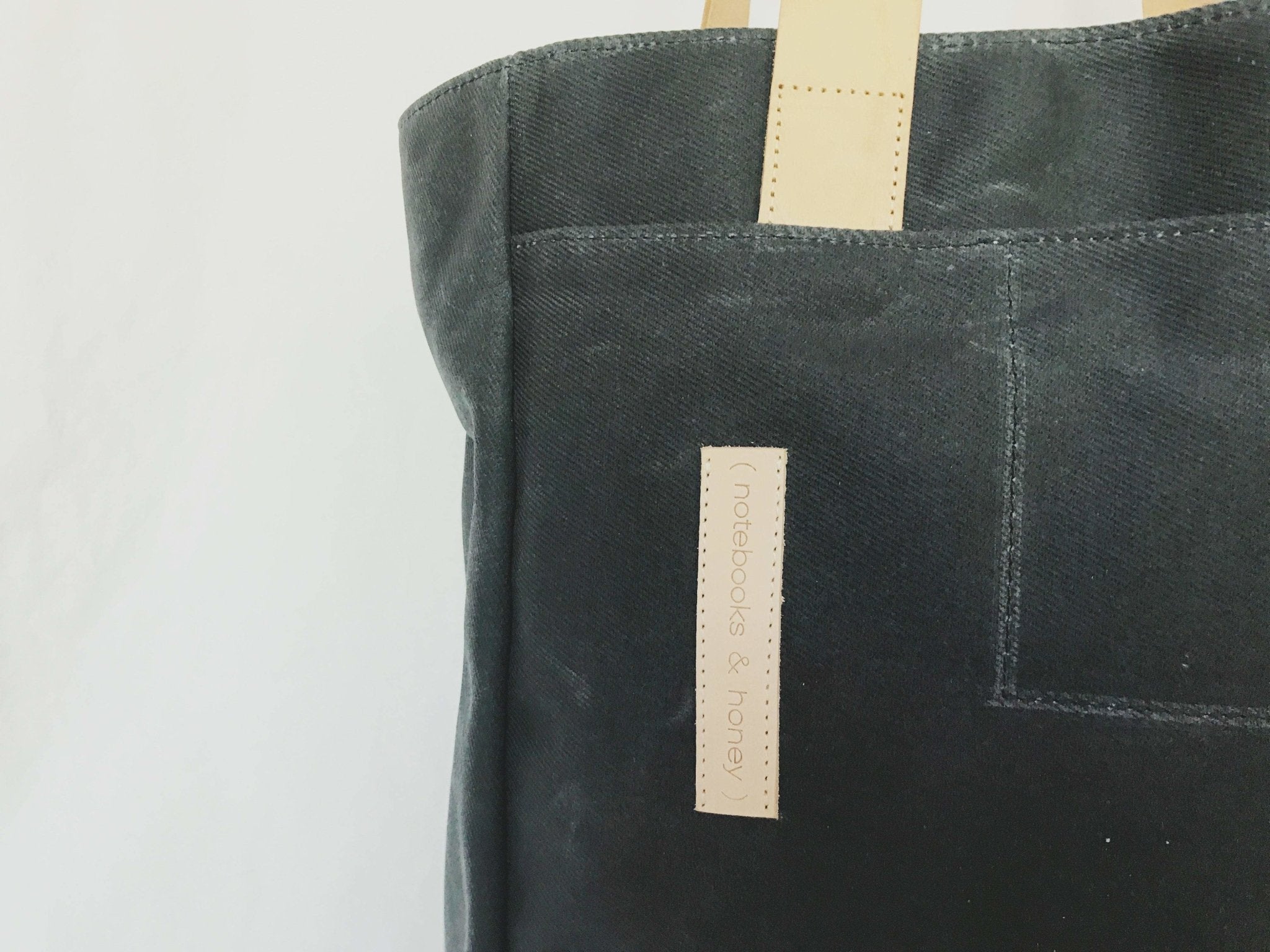 Lifestyle photo showing Charcoal Grey Wax Canvas Tote Bag - The Morning Person in use - notebooks & honey