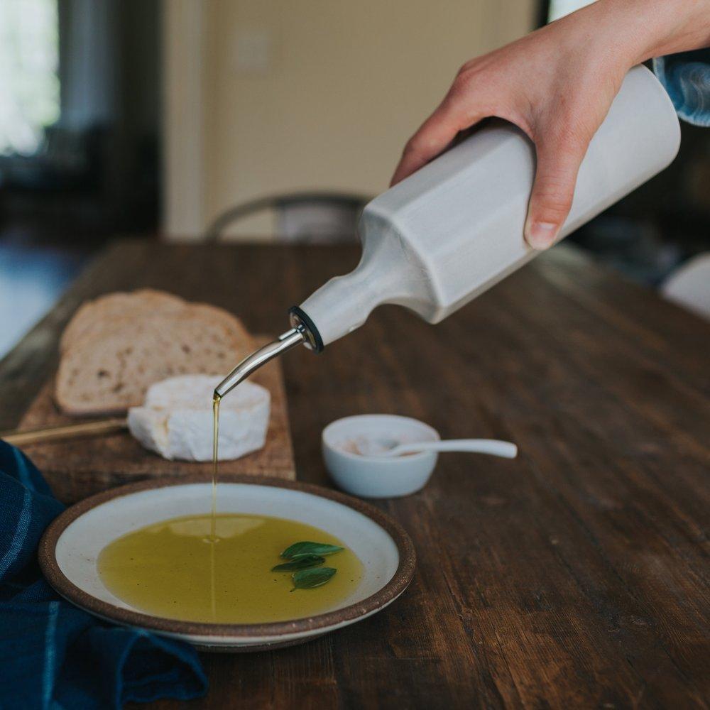 Lifestyle photo showing Elixir Porcelain Olive Oil Dispenser in use - Ember Collective